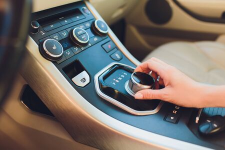 Close up Young woman hand on automatic gear shift, shifting gearbox in car.Driver woman hand holding automatic transmission or variable speed drive in car, shifting gear stick before driving car.の写真素材