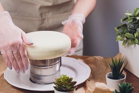 Confectioner makes a wedding cake with confectionery bag at kitchen.