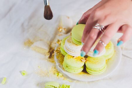 Different sweet fresh french macarons in girls hand