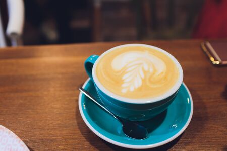 Cup of coffee on wooden table, top view.