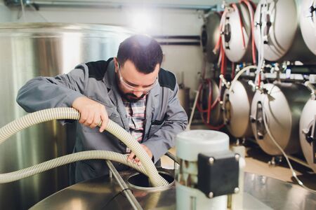 Portrait of brewer who is making beer on his workplace in the brew-house..