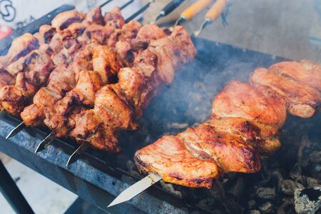 Grilled kebab cooking on metal skewer. Roasted meat cooked at barbecue. BBQ fresh beef meat chop...