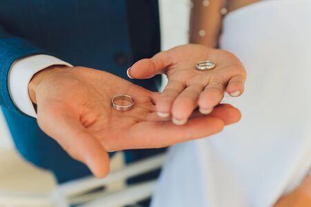 Close-up. Hand of bride and groom. Bride and groom hold hands. Focus on the rings. Bouquet in hand.