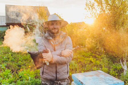 Experienced beekeeper grandfather teaches his grandson caring for bees. Apiculture. The concept of transfer of experience.の写真素材