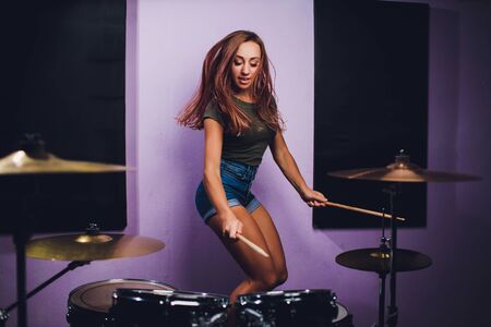 Photograph of a female drummer playing a drum set on stage.