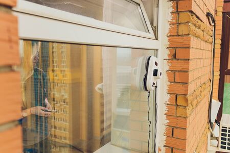 Vacuum cleaner robot cleaning window in high building outdoorの写真素材