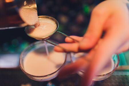 A bartender makes a cocktail over the marble bar counter