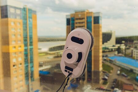 Vacuum cleaner robot cleaning window in high building outdoorの写真素材