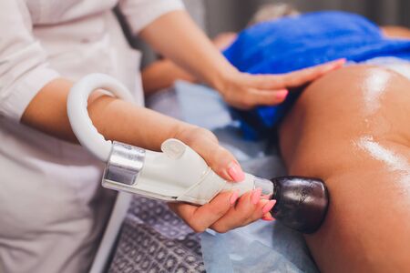 Cropped view of cosmetologist with roller doing buttocks starvac massage.