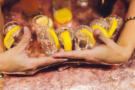 Bartender pouring strong alcoholic drink into small glasses on bar, shots.の写真素材