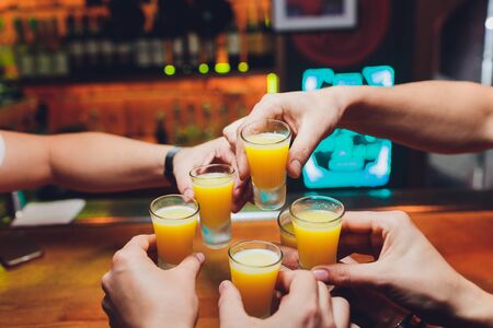 Bartender pouring strong alcoholic drink into small glasses on bar, shots.