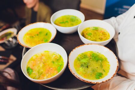 Smooth creamy soup of english smoked cheddar cheese and broccoli with toasted bread on a white tray with spoons, close-up, horizontal.の写真素材