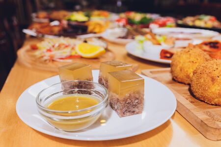 Jellied, aspic cooked from beef, pork, chicken with mustard on a plate close-up.の写真素材