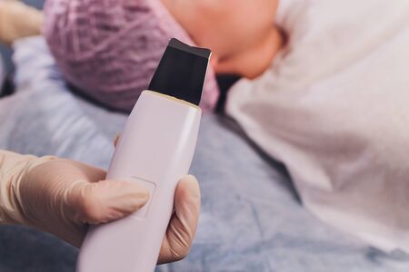 receiving ultrasonic facial exfoliation procedure of ultrasonic cleaning of face in beauty salon.Modern Ultrasonic skin equipment for ultra peel treatment.の写真素材