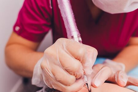 tattooist is using gun tool for eyebrows tattoo closeup.の写真素材