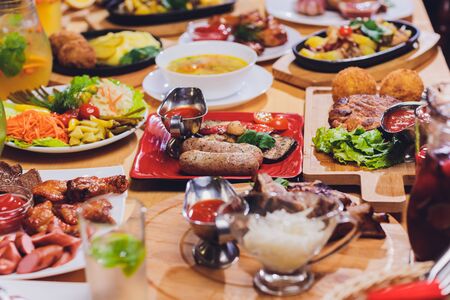 Dinner party food concept. Dinner table with grilled sausage, tortilla wraps, beer drink and different dishes on wooden table, rustic styleの写真素材