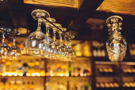 Group of empty wine glasses hanging from metal beams in a barの写真素材