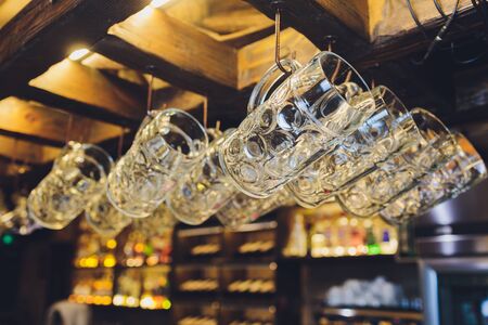 Group of empty wine glasses hanging from metal beams in a bar.