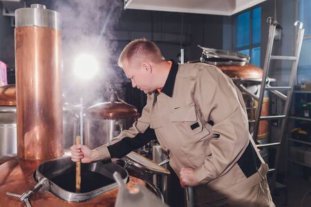 Brewer in brewhouse pouring out the malt to the tank.の写真素材