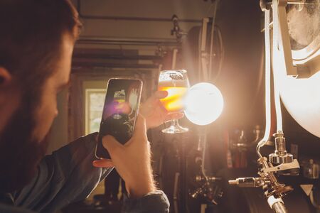 Mature man examining the quality of craft beer at brewery. Inspector working at alcohol...