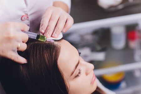 Needle mesotherapy. Cosmetic been injected in woman's head. Thrust to strengthen hair and their growthの写真素材