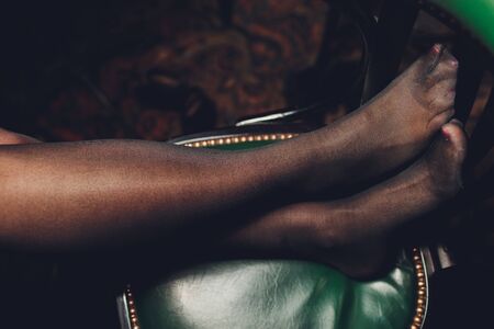 Pair of legs in black stockings on a green chair.の写真素材