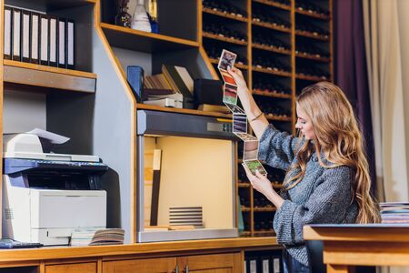 Portrait of smiling female interior designer sitting at office desk. color comparison equipment