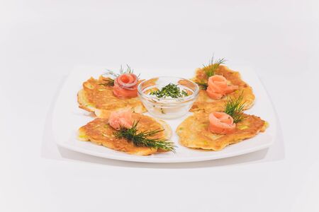 A plate of potato pancakes decorated with basil leaves on the tableの写真素材