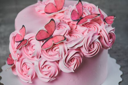 Overhead view of a freshly baked cake decorated with pink icing sugar roses displayed on a cake stand over a black background with copyspace.の写真素材