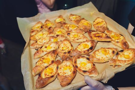 Process of cooking traditional adjarian georgian and armenian cuisine, hachapuri khachapuri with suluguni cheese and egg yolk on a wooden table with chief's hands in the backgroundの写真素材