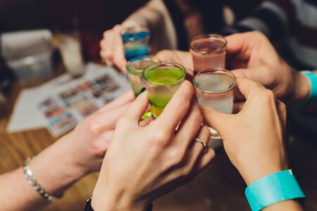 Close up shot of group of people clinking glasses with wine or champagne in front of bokeh background older people handsの写真素材