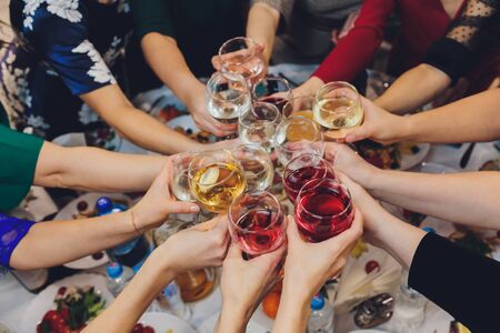 Close up shot of group of people clinking glasses with wine or champagne in front of bokeh background. older people hands.の写真素材