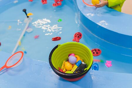 fishing in the paddling pool. Childrens toys in the pool. Toy fish fishing rod. Cheerful children fishing, fishing in the paddling pool.の写真素材