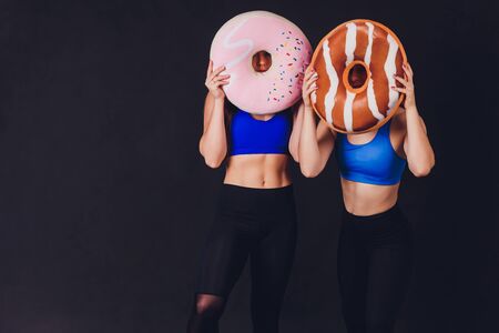 Young fitness woman with gloved hands featuring tight abdominal muscles over black background with copy space Muscular single fit woman with long blonde hair and abs Fitness people training.の写真素材