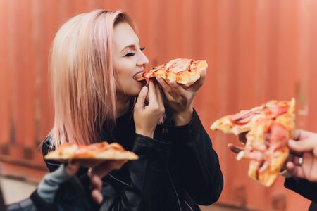 Girl eating a delicious pizza while sitting on a motorcycle.の写真素材