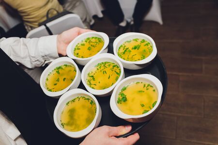 Waiter holding tray with plates of soup in the restaurant