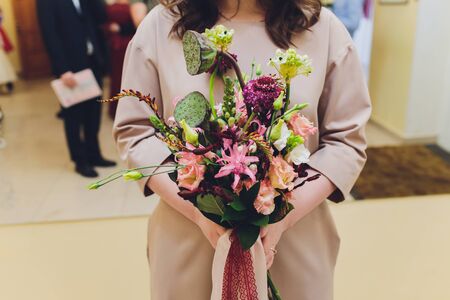 Unusual wedding stylish bouquet with orange and white flowers in hands of a brideの写真素材