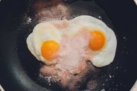 Appetizing photograph of scrambled eggs from one chicken egg in a pan with boiling sunflower oil
