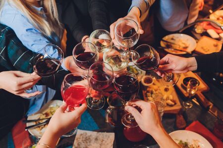 Close up shot of group of people clinking glasses with wine or champagne in front of bokeh background. older people hands.の写真素材