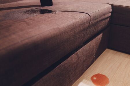Red wine spilled on a brown couch sofa.の写真素材