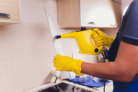 Professional janitor cleaning mesh filter of cooker hood in kitchen, closeupの写真素材