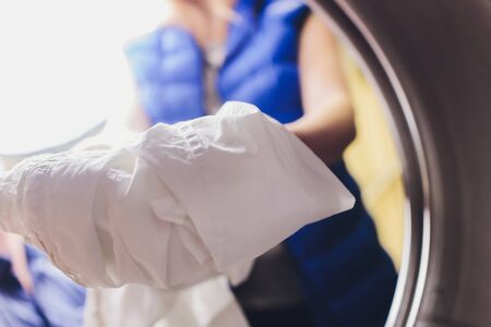 Hands to load the Laundry in the washing machine at the dry cleaners.の写真素材