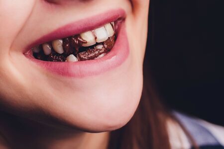 Closeup of smiling woman eating chocolate bar.の写真素材