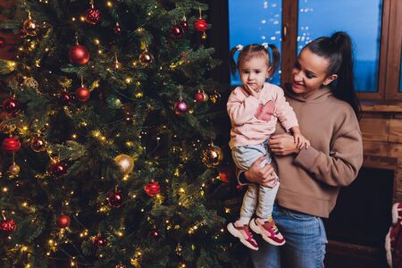 Merry Christmas and Happy Holidays Cheerful mom and her cute daughter girl exchanging gifts. Parent...