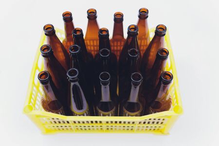 Dusty vintage yellow beer crate with empty brown beer bottles on white backgroundの写真素材