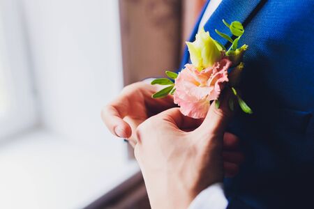 Boutonniere on groom's wedding jacket. White and pink rose wedding boutonniere on suit of groomの写真素材