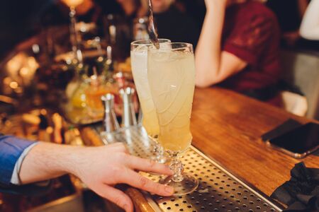 Bartender making a cocktail with help of the bar equipment arranged on the bar counter