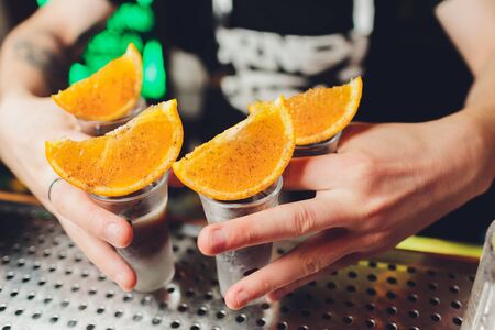Bartender pouring strong alcoholic drink into small glasses on bar, shotsの写真素材