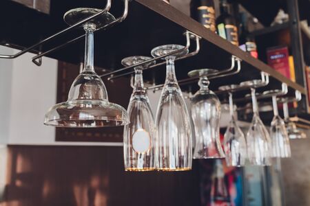 Closeup many upside down empty clear transparent crystal upturned wine glasses hanging in straight...