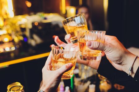 Clinking glasses with alcohol and toasting, party whiskey iceの写真素材